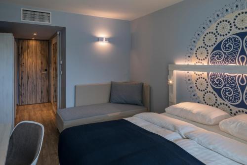 a bedroom with a bed and a couch and a chair at Falkensteiner Club Funimation Borik in Zadar