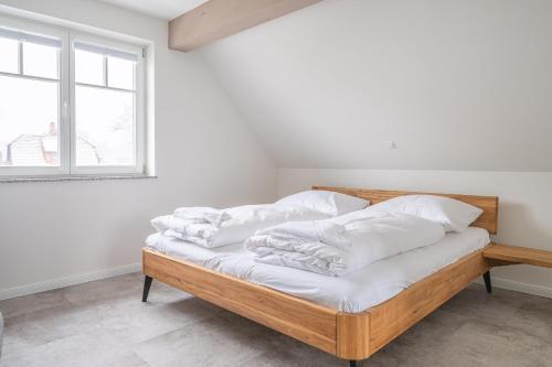 een slaapkamer met een bed met witte lakens en een raam bij Haus Badestrand Badestrand 3 in Born