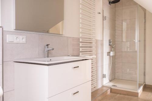 een witte badkamer met een wastafel en een douche bij Haus Badestrand Badestrand 3 in Born