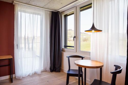 a room with a table and chairs and windows at Tailormade Hotel RIGIBLICK Küssnacht in Küssnacht
