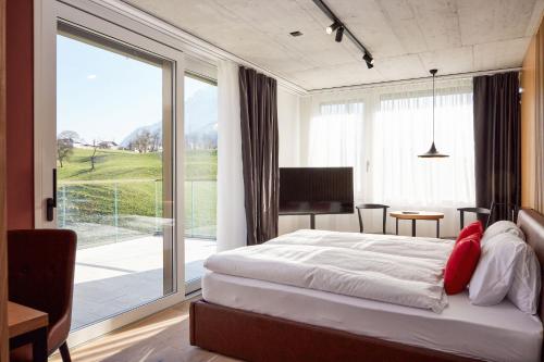 a bedroom with a bed and a large window at Tailormade Hotel RIGIBLICK Küssnacht in Küssnacht