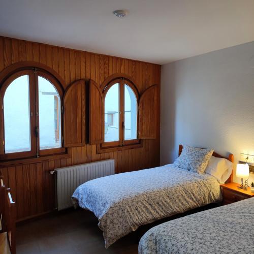 a bedroom with two beds and two windows at Pensión Mesón La Lonja - Herbers in Herbés