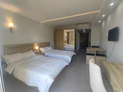 a hotel room with two beds and a desk at You are welcome to Mido Shallet in Naqādah