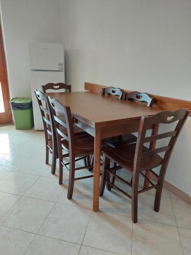 a wooden table with four chairs and a refrigerator at Casa Gargiulo in Massa Lubrense