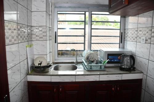 una cucina con lavandino e finestra di Spetiv Guesthouse a Douala