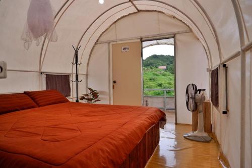 1 dormitorio con cama de color naranja y ventana en Mon Jaw Doi at Monjam en Chiang Mai