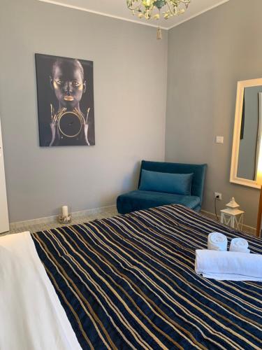 a bedroom with a bed and a blue chair at Maison belle Vue in Taormina