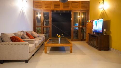 sala de estar con sofá y TV en Misty Hills Villa Kadugannawa, en Kadugannawa