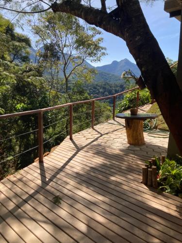 a wooden deck with a table and a tree at O Chalé mais bucólico de Araras. Vista linda in Araras Petropolis