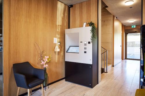 a hallway with a black chair and a white refrigerator at Tailormade Hotel RIGIBLICK Küssnacht in Küssnacht