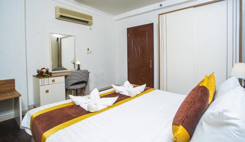a bedroom with a large white bed with pillows at La Villa Suites Hotel in Doha