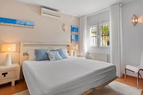 Un dormitorio con una gran cama blanca y una ventana en Casa Mosa, en Marbella