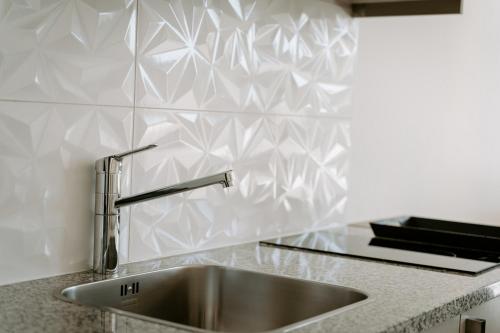 Villas Elini في Perdika: حوض حديد قابل للصدأ في مطبخ به بلاط أبيض