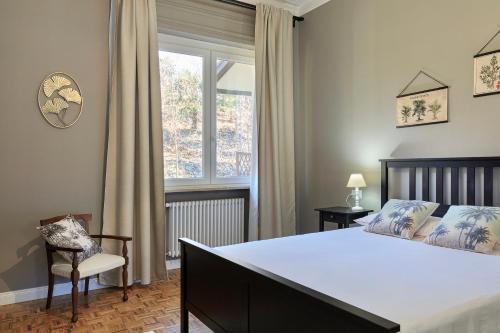 a bedroom with a bed and a chair and a window at Villa Caramino in Fara Novarese