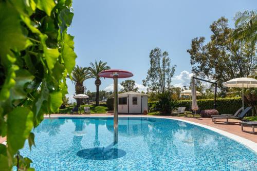 a swimming pool with a umbrella in the middle at Hotel Arbatasar in Àrbatax