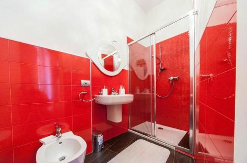 een rode badkamer met een wastafel en een douche bij B&B BuongiornoNotte in Bobbio
