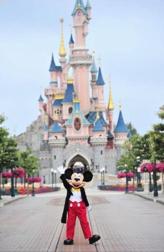 a figurine of mickey standing in front of a castle at Appart COSY F2 Disneyland/Val d'Europe in Montévrain