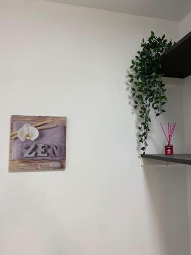 a white wall with a clock and a plant at Appart COSY F2 Disneyland/Val d'Europe in Montévrain