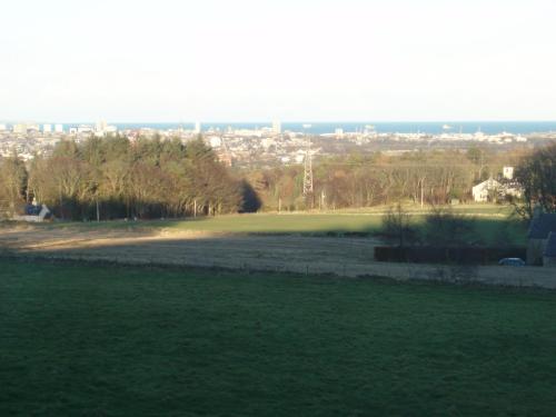 een groen veld met een stad op de achtergrond bij Lochend Farmhouse in Aberdeen