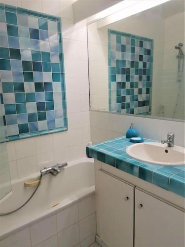 une salle de bain avec un lavabo, une baignoire et un miroir dans l'établissement Appartement Mas de la Mer, 5mn plage, piscine, à Saint-Aygulf