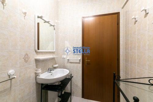 een badkamer met een wastafel en een houten deur bij Costa Del Sol in Lido di Jesolo