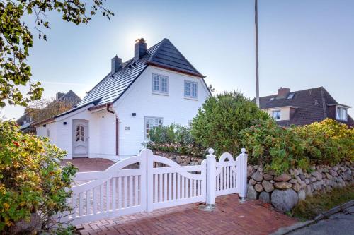 a white fence in front of a white house at Haus Gordon in Wenningstedt