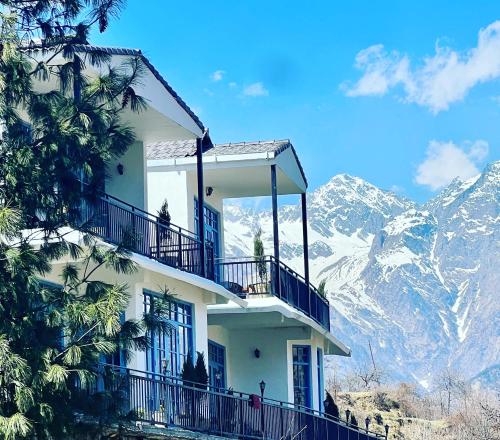 a white building with a balcony on top of a mountain at Faraway Cottages, Auli in Joshīmath