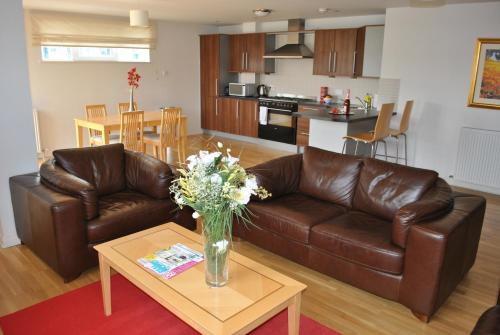 a living room with a brown leather couch and a table at Dreamhouse Apartments Edinburgh City Centre in Edinburgh