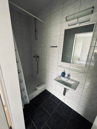 a bathroom with a sink and a mirror and a tub at Gästehaus Hanseat in Bremerhaven