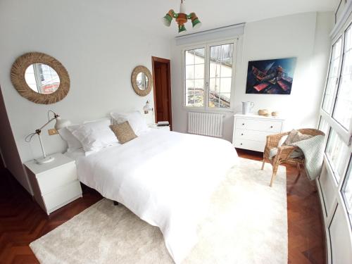 a white bedroom with a bed and a window at Sobre la Ría in Viveiro