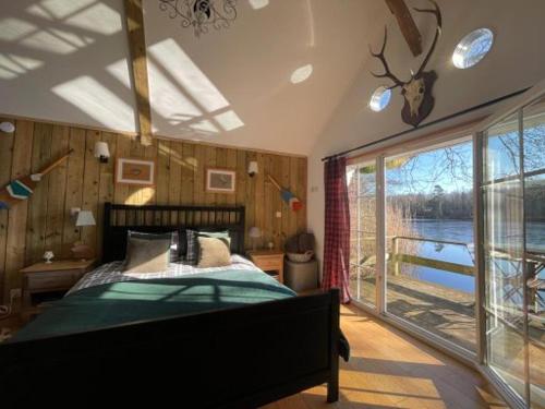 1 dormitorio con cama y ventana grande en La cabane sur l'eau, en Cul-des-Sarts