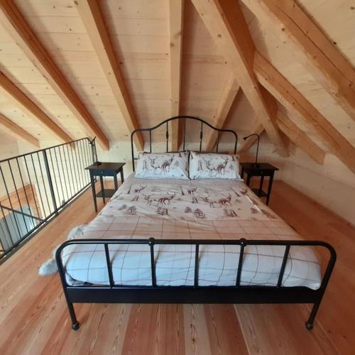 Ce lit se trouve dans un dortoir doté d'un plafond en bois. dans l'établissement Chalet Ridente con Patio al Gufo, à Ovaro
