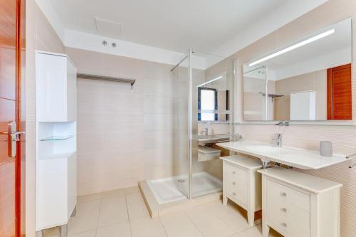 une salle de bain blanche avec un lavabo et un miroir dans l'établissement Tajinaste villa, à Adeje