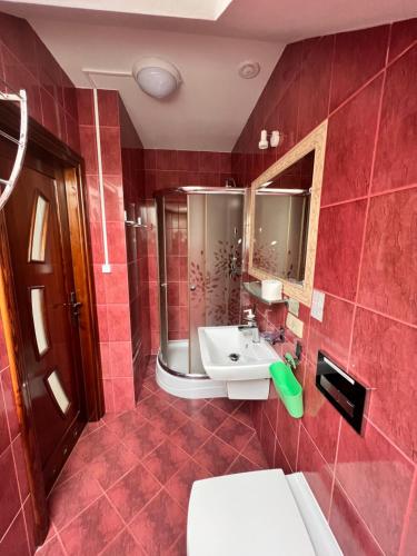 Baño rojo con lavabo y aseo en Rybaczówka Golub-Dobrzyń en Golub-Dobrzyń