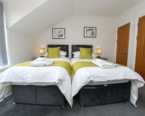 two twin beds in a bedroom with two lamps at Luxe Living Guest House-Sleeps 6-Private Parking-Free WIFI-Beach-City in Swansea