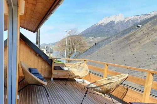 a balcony with chairs and a table and mountains at La maison du Lac in Doussard