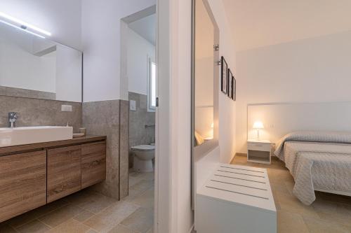 a bathroom with a sink and a toilet and a bed at Villa Arca by RivedelSalento in Otranto