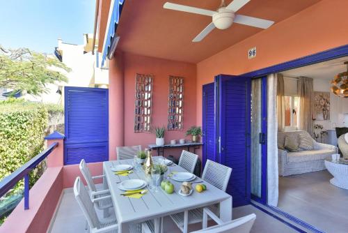 a white table and chairs on a balcony with a blue door at Bahia Meloneras MJV96 by VillaGranCanaria in Meloneras