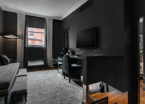 a black room with a desk and a television at The Franklin London - Starhotels Collezione in London