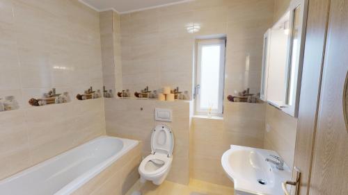 a bathroom with a tub and a toilet and a sink at Harmony Apartment VRT in Şelimbăr