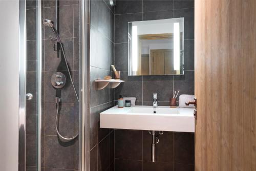 La salle de bains est pourvue d'un lavabo et d'une douche avec un miroir. dans l'établissement Résidence Pierre & Vacances Premium Les Chalets du Forum, à Courchevel