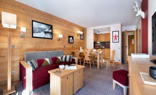 a living room with a couch and a dining room at Résidence Pierre & Vacances Premium Les Chalets du Forum in Courchevel