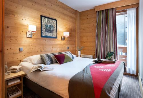 a bedroom with a bed with a book on it at Résidence Pierre & Vacances Premium Les Chalets du Forum in Courchevel