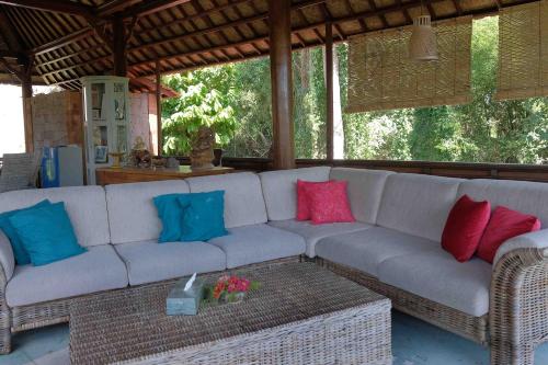 a white couch with colorful pillows on a patio at Sua Bali in Ubud