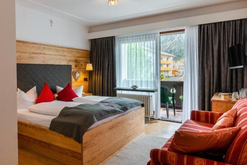a bedroom with a bed and a couch and a window at Hotel Bichlerhof in Mittenwald