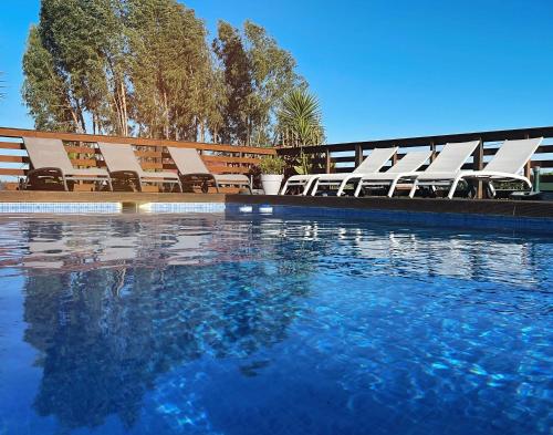 a group of chairs sitting next to a swimming pool at Herdade do Kuanza in Zambujeira do Mar