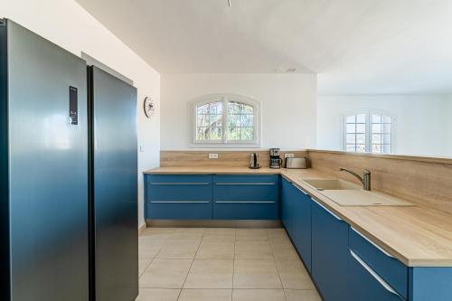 une cuisine avec des armoires bleues et un évier dans l'établissement Superbe appartement 2 chambres en haut de Villa, à Saint-Mandrier-sur-Mer