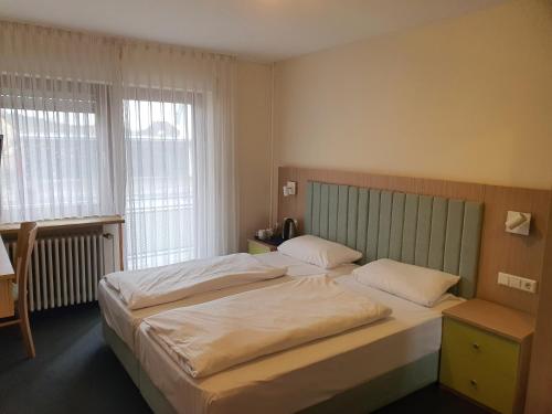 蓋辛根的住宿－Hotel Gasthof Sternen，一间卧室设有两张床和两个窗户。