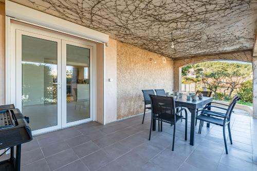 une salle à manger avec une table et des chaises sur un patio dans l'établissement Bas de villa refait à neuf, climatisation et terrasse vue mer, à Saint-Mandrier-sur-Mer