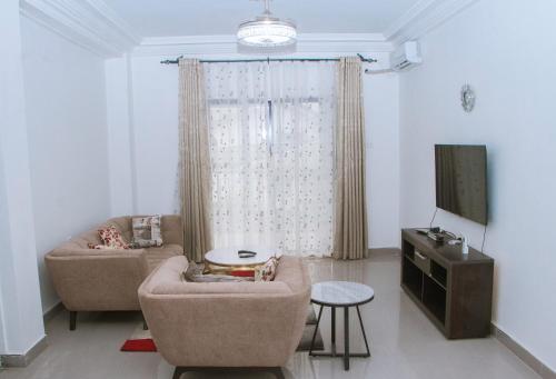 a living room with two couches and a tv at Candide Guest House in Limbe